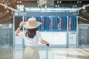 jonge vrouwenhand die bagagehandvat houdt alvorens vluchttijd in luchthaven, vervoer, verzekering, reis en vakantieconcepten te controleren foto