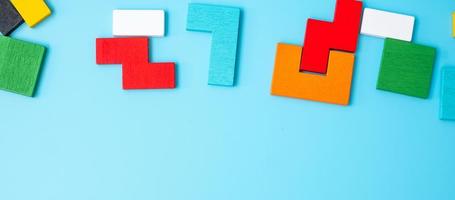 kleurrijke houten puzzelstukjes op blauwe achtergrond, geometrische vorm blok met kopie ruimte. concepten van logisch denken, raadsel, oplossingen, rationeel, strategie, wereldlogicadag en onderwijs foto