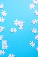 groep witte puzzelstukjes op blauwe achtergrond. concept van oplossingen, missie, succes, doelen, samenwerking, partnerschap, strategie en puzzeldag foto