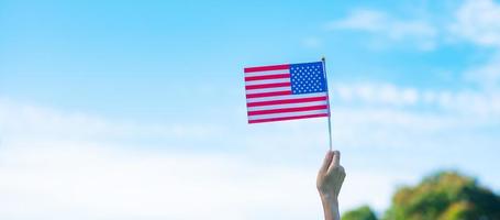 hand met de vlag van de Verenigde Staten van Amerika op blauwe hemelachtergrond. usa vakantie van veteranen, gedenkteken, onafhankelijkheid en dag van de arbeid concept foto