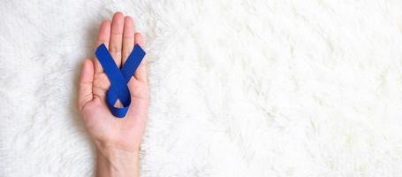 maart colorectale kanker bewustzijn maand, man met donkerblauw lint voor het ondersteunen van mensen die leven en ziekte. gezondheidszorg, hoop en wereldkankerdagconcept foto