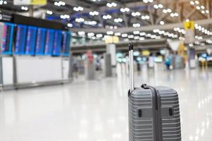 bagagetas in de internationale luchthaventerminal, trolleykoffer met informatiebord op de achtergrond van het vliegveld. transport-, verzekeringen-, reis- en vakantieconcepten foto
