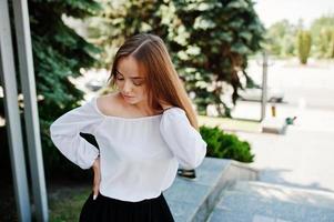 portret van een geweldige vrouw in witte blouse en brede zwarte broek poseren met pijnbomen op de achtergrond. foto