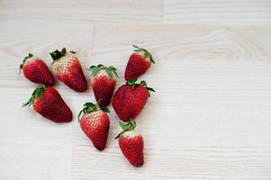 acht aardbeien die op tafel liggen in de vorm van een hart. foto