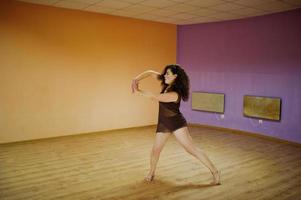 krullend brunette plus size model doet acrobatiek in de dansruimte. foto