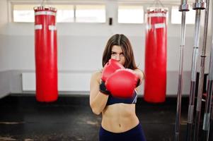 jonge mooie vrouw, draag bokshandschoenen die oefeningen doen en hard werken in de sportschool en genieten van haar trainingsproces. foto