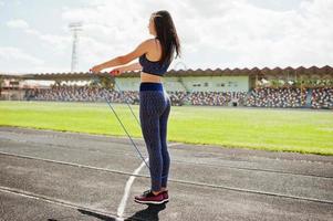 portret van een gelukkige jonge vrouw in sportkleding die oefeningen doet met springtouw. foto