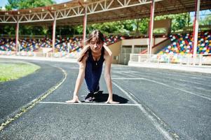 portret van een sterk fit meisje in sportkleding die in het stadion loopt. foto