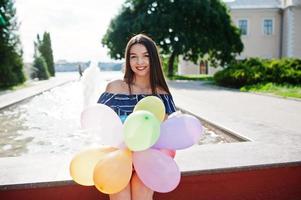 prachtige brunette meisje op straat van de stad met ballonnen bij de hand. foto