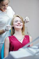 prachtige jonge vrouwelijke tandarts die de tanden van haar patiënt controleert in een speciaal uitgeruste kast. foto