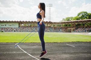 portret van een gelukkige jonge vrouw in sportkleding die oefeningen doet met springtouw. foto