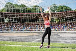 fitness sportief meisje in sportkleding en zonnebril poseerde bij stadion voetbal poorten buitensporten. gelukkige sexy vrouw. foto