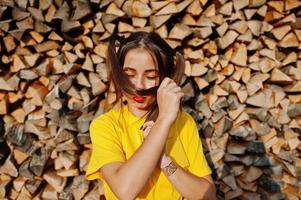 jong grappig meisje met lichte make-up, staarthaarslijtage op geel shirt tegen houten achtergrond. foto