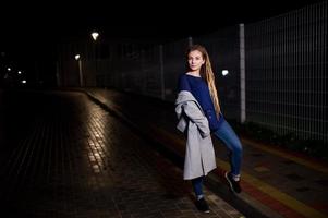 meisje met dreadlocks lopen 's nachts straat van de stad. foto