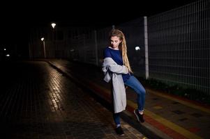 meisje met dreadlocks lopen 's nachts straat van de stad. foto