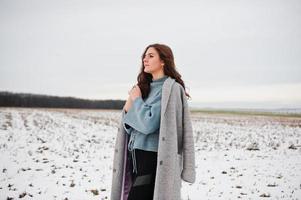 zachtaardig meisje in grijze jas tegen sneeuwlandschap. foto