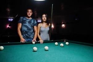 vrouw in jurk pool spelen met een man in een pub. foto