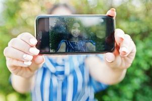 mobiele telefoon bij de hand met prachtige brunette meisje op het scherm. foto