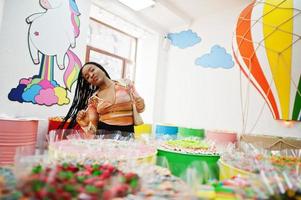 Afro-Amerikaanse duizendjarige dame bij snoepwinkel met lolipops. foto