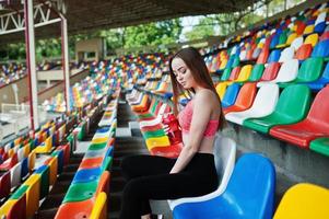 fitness sportieve meisje in sportkleding zittend op stadion stoelen buitensporten. gelukkige sexy vrouw met sportflesmodel. foto