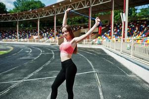 fitness sportief meisje in sportkleding bij een voetbalstadion buitensporten. gelukkig sexy vrouw training met touw. foto