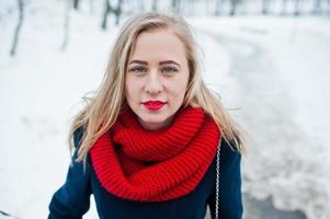 portret van blond meisje in rode sjaal en jas op winterdag. foto