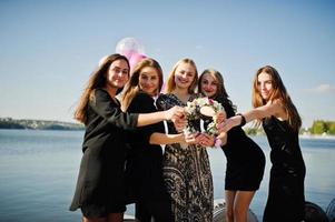 vijf meisjes dragen op zwart plezier tegen meer op vrijgezellenfeest. foto