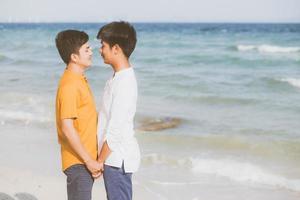 homoseksueel portret jonge aziatische paar permanent samen op het strand in de zomer, azië homo hand in hand gaan zee voor vrije tijd en ontspannen met romantisch en gelukkig in vakantie op zee, lgbt met juridisch concept. foto