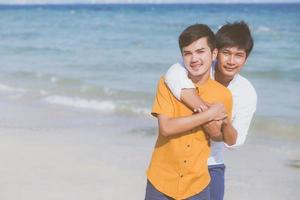 homoseksueel portret jong aziatisch paar staande knuffel samen op het strand in de zomer, azië homo gaand toerisme voor vrije tijd en ontspannen met romantisch en geluk in vakantie op zee, lgbt-concept. foto