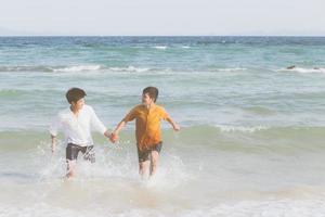 homoseksueel jong aziatisch stel loopt met vrolijk samen op het strand in de zomer, azië homo gaand toerisme voor vrije tijd en ontspan met geluk in vakantie op zee, lgbt juridisch concept. foto