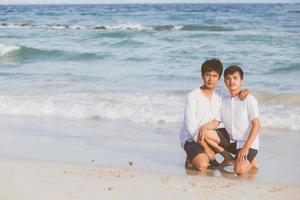 jonge aziatische paar homo glimlachend romantische tekening woord tekst liefde samen op zand in vakantie, homoseksueel gelukkig en leuk met liefde zittend op zand op het strand in reizen zomer, lgbt juridisch concept. foto