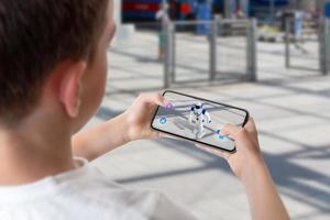 jongen programmeert en bestuurt de robot op straat via augmented reality technologie concept foto