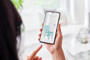 vrouw met augmented reality-app zet een houten stoel in de woonkamer. virtuele meubelplaatsing met mobiel concept foto