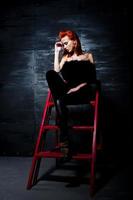 fashion model roodharig meisje met oorspronkelijk make-up als luipaard roofdier tegen stalen muur. studioportret op ladder. foto