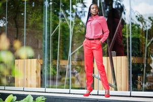 mooie vlechten zakelijke afro-amerikaanse dame heldere bazige persoon vriendelijke slijtage kantoor rood shirt en broek. foto