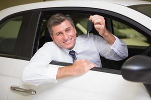 glimlachende mens die sleutelzitting in zijn auto houdt foto
