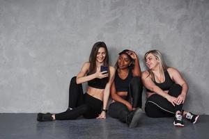 kijk wat ik heb gevonden. groep multi-etnische vrouwen die in de studio zitten tegen een grijze achtergrond foto