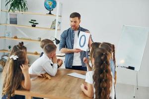 het leren van de nieuwe letter o. groep kinderen studenten in de klas op school met leraar foto