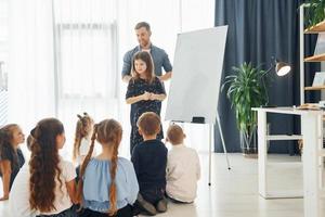 meisje schrijven op het bord. groep kinderen studenten in de klas op school met leraar foto