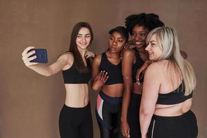 laten we een foto maken. groep multi-etnische vrouwen die in de studio staan tegen een bruine achtergrond