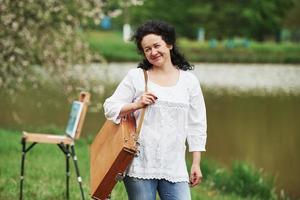 lenteweer. volwassen schilder met koffer met instrumenten maak een wandeling in het prachtige park foto