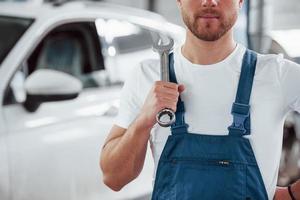 man met lichte baard. werknemer in het blauw gekleurde uniform werkt in de autosalon foto