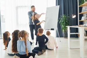 meisje schrijven op het bord. groep kinderen studenten in de klas op school met leraar foto