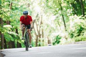 hete temperatuur. fietser op een fiets is op de asfaltweg in het bos op zonnige dag foto