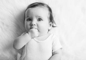 schattige babymeisje met hand in haar mond foto