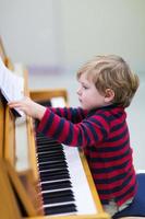 twee jaar oude peuterjongen die piano speelt