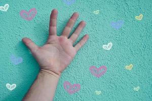 hand op de blauwe muur met hartenvormen, valentijnsdag foto