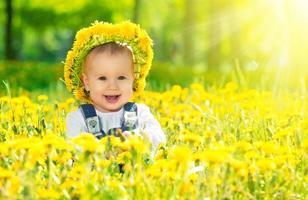 gelukkig babymeisje in krans op weide met gele bloemen foto