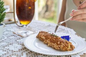 zelfgemaakte bladerdeeg gefrituurde eclairs met vanille crème topping met amandelen moer op witte plaat over tafelblad met kant tafelkleed. traditioneel Frans dessert. selectieve focus foto