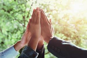 zakelijk team dat high five geeft met zonneschijnachtergrond foto